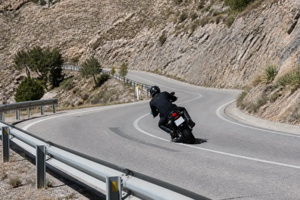 Motorista inclinado en una curva de carretera de montaña