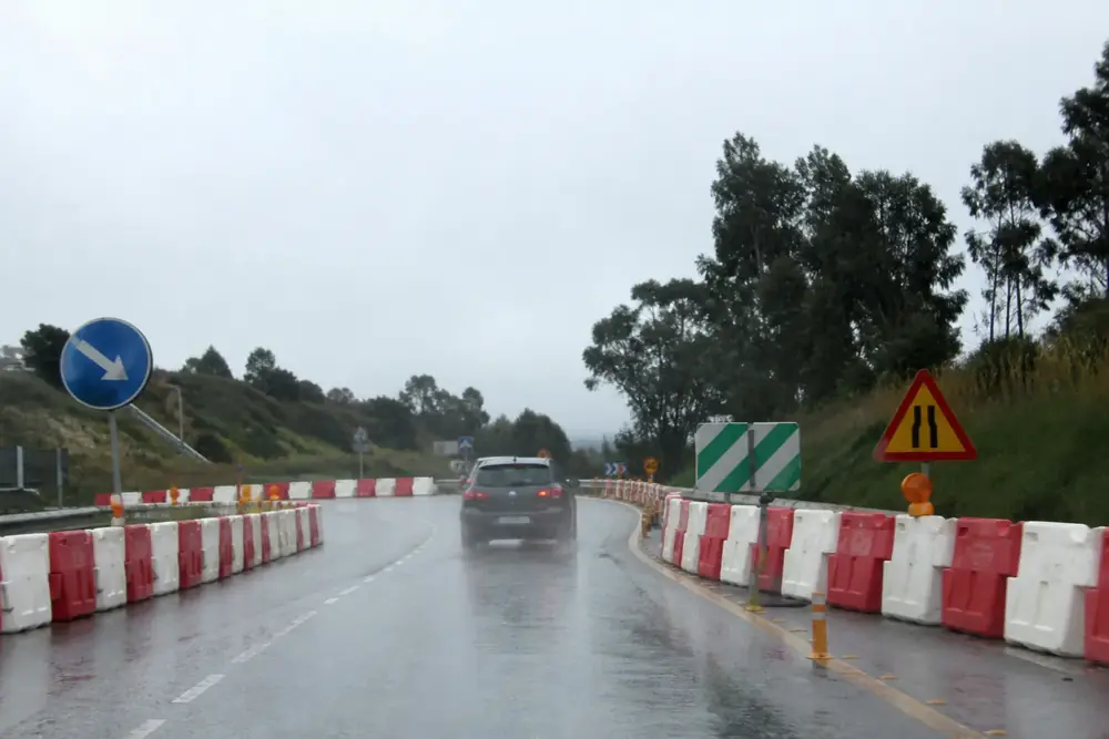 Obras con barreras rojas y blancas en una carretera mojada